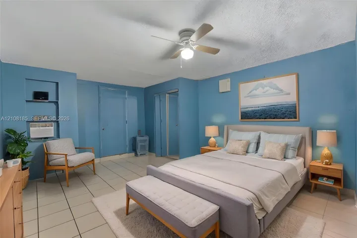 Ceramic tile flooring, built-in wall shelving, and a ceiling fan with integrated lighting