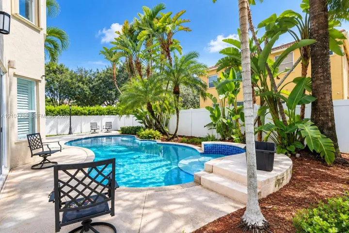 Private outdoor space featuring a swimming pool, integrated spa, concrete patio, and perimeter privacy fencing
