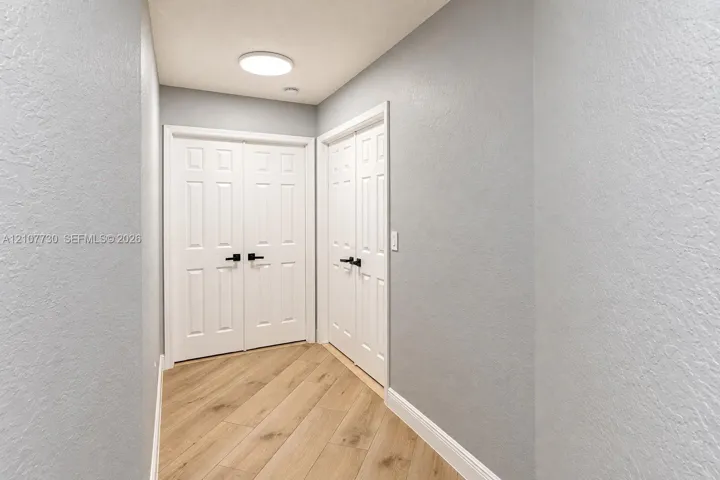 Wood-finish flooring, light gray walls, white six-panel double doors, and matte black hardware
