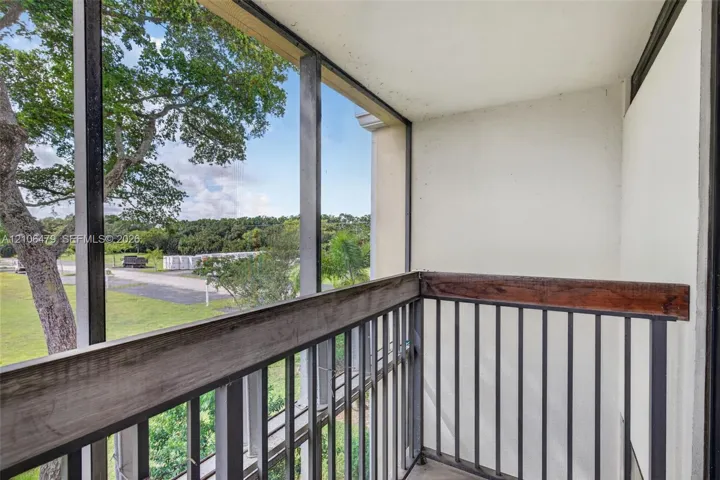 Screened balcony featuring a metal railing with a wood-finish top rail