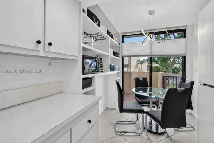 Built-in white cabinetry featuring open shelving, tile flooring, modern sculptural pendant lighting, and sliding glass doors with direct exterior access