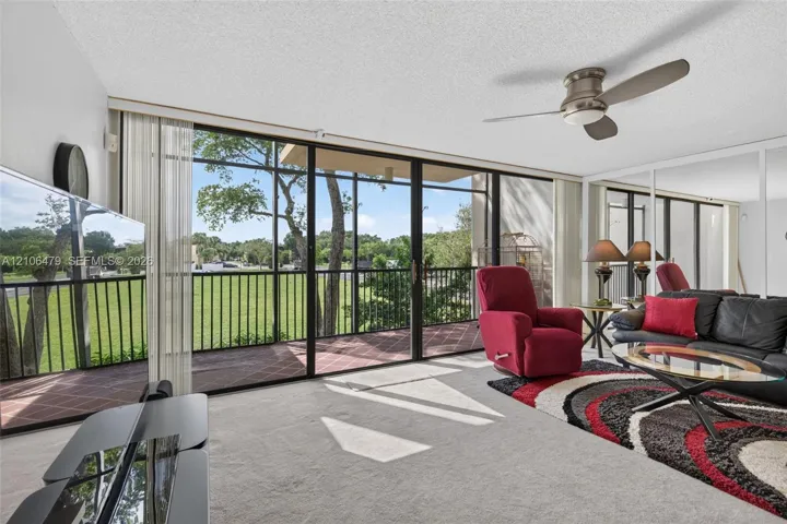 Floor-to-ceiling sliding glass doors opening to a screened balcony, mirrored wall panels, and a central ceiling fan