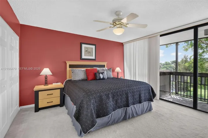 Floor-to-ceiling sliding glass doors, private balcony, ceiling fan with light kit, and double-door closet