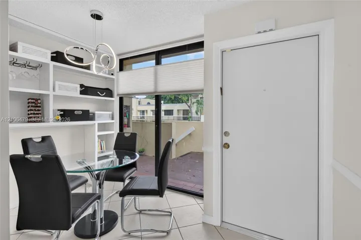 Built-in white shelving, tile flooring, contemporary multi-ring pendant lighting, and large sliding glass door with external patio access