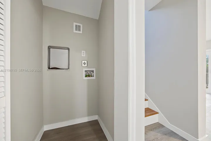 Neutral interior alcove featuring wood-finish flooring and integrated wall-mounted utility access panels