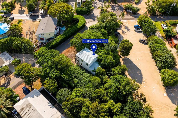 Aerial perspective of a multi-story residence featuring a metal roof, nestled within a lot characterized by mature tree canopy and established vegetation