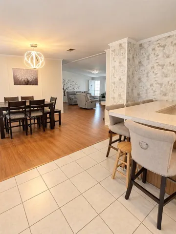 Kitchen featuring a breakfast bar with stone-composite countertop, light-toned ceramic tile flooring, wood-finish flooring, and a contemporary geometric pendant light fixture