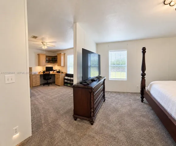 Neutral wall finish, carpeted flooring, built-in wooden cabinetry, ceiling fan, and window blinds