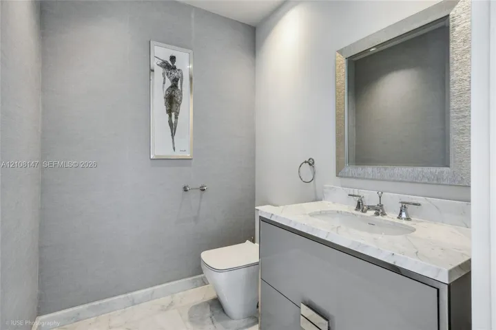 Wall-mounted vanity featuring high-gloss cabinetry, stone countertop with an integrated basin, polished chrome fixtures, and textured wall treatment