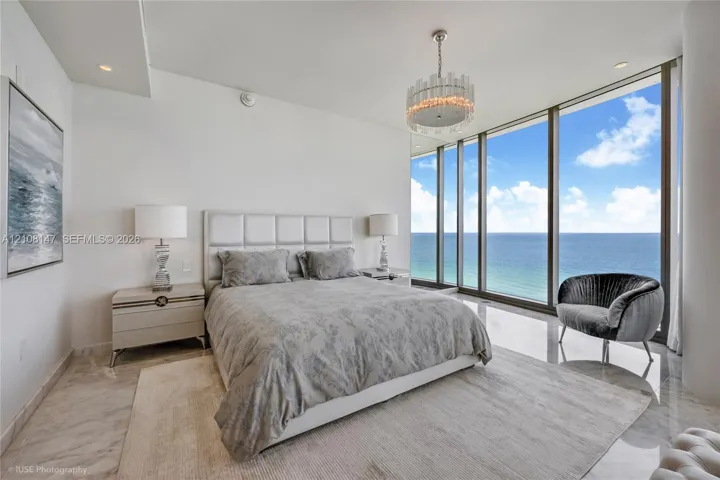 Floor-to-ceiling windows, polished stone flooring, recessed ceiling lighting, and a crystal drum chandelier