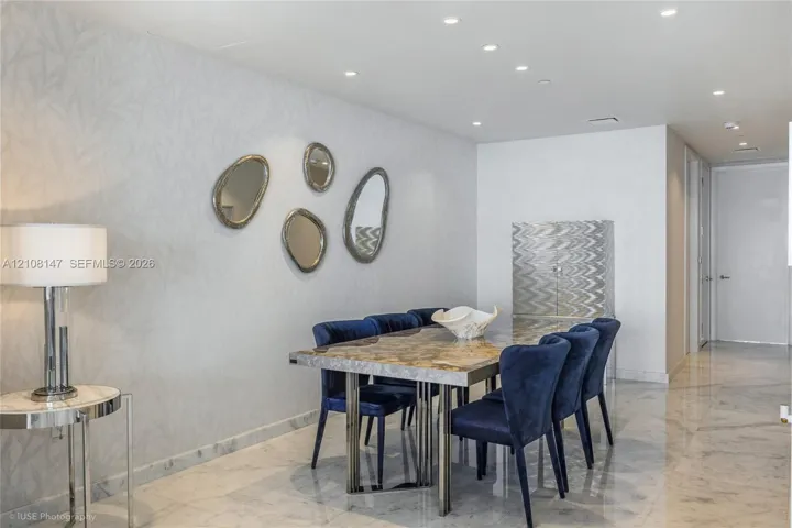 Interior space featuring polished stone flooring, textured wall covering, and recessed lighting throughout