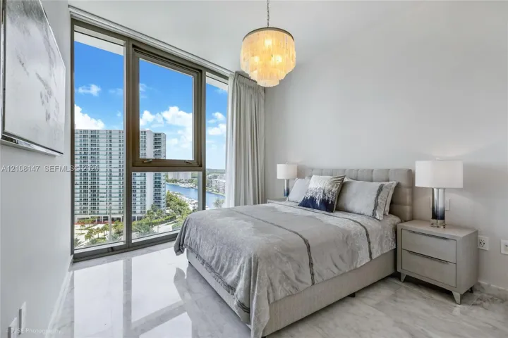 Floor-to-ceiling windows, polished stone flooring, and tiered crystal chandelier fixture