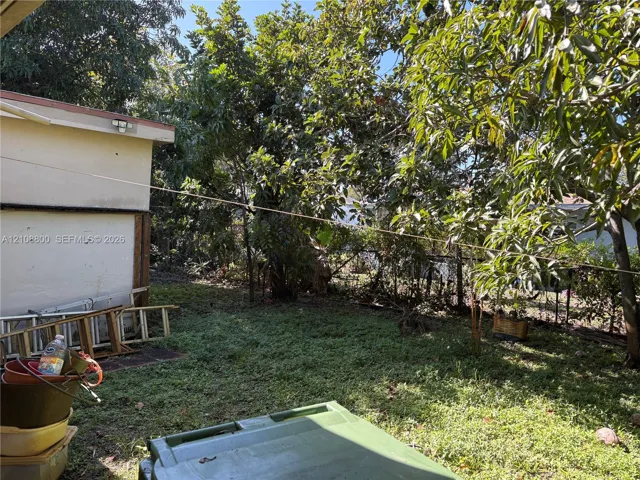 Exterior space featuring mature trees and a grass-covered lot