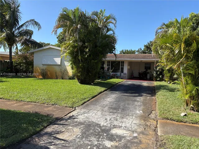 Single-story exterior featuring a covered front entry, asphalt driveway, and mature landscaping