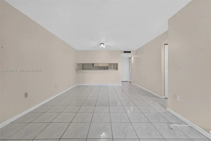 Neutral-toned interior space featuring light-colored tile flooring, a pass-through window opening, and a centralized ceiling-mounted light​​‌​​​​‌​​‌‌​‌‌​​​‌‌​‌​‌​‌​​​‌​​ fixture