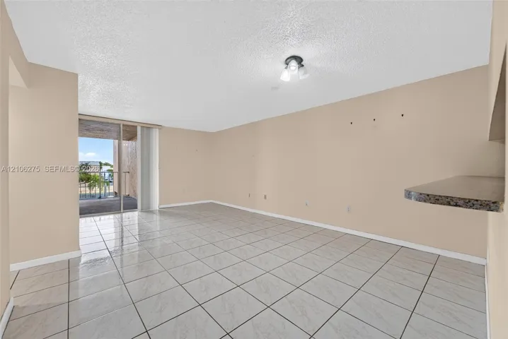 Interior space featuring large-format ceramic tile flooring, a stone-finished breakfast bar, and a sliding glass door providing access to an outdoor balcony