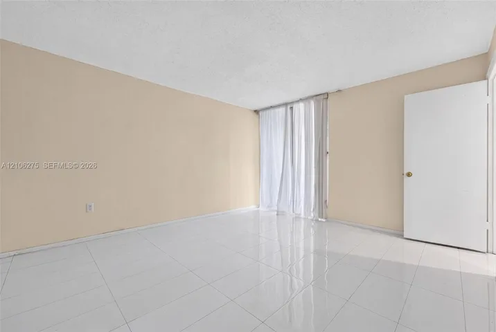 Interior space featuring neutral wall paint, white tile flooring, and a single swing door