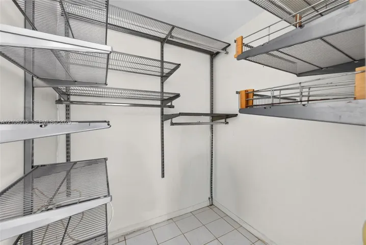 Storage area featuring adjustable metal shelving units, integrated wire racking, and tile flooring