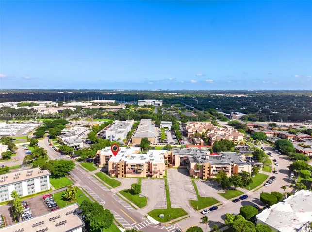 Aerial view of a multi-story residential complex featuring stucco exterior walls, private balconies, and dedicated asphalt parking