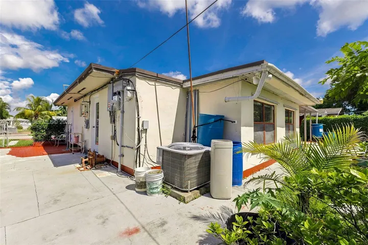 Stucco exterior featuring concrete paved surfaces, window shutters, and central air conditioning unit