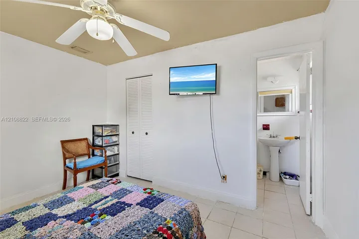 Room featuring light-toned tile flooring, dual-panel closet doors, and a ceiling fan with integrated lighting