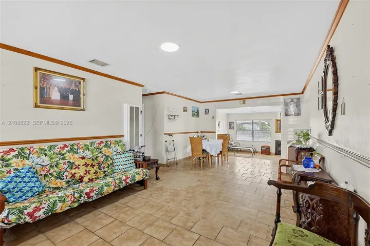 Open-concept interior featuring light-toned tile flooring, chair rail molding, and recessed ceiling lighting