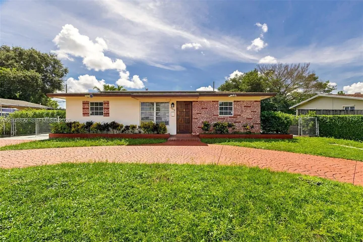 Single-story exterior featuring a brick facade, stucco siding, a patterned concrete driveway, and exterior shutter accents
