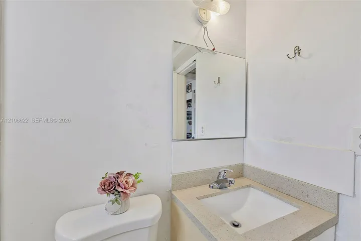 Wall-mounted mirror, vanity with a light-toned countertop, and integrated sink with a polished metal faucet