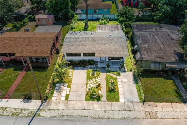 Exterior view of a single-story residence featuring a shingled gable roof, a concrete driveway, a segmented paver walkway, and landscaped front grounds