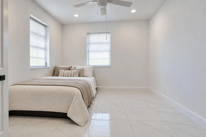 Neutral-toned interior featuring large-format tile flooring, recessed lighting, and a white ceiling fan with integrated light