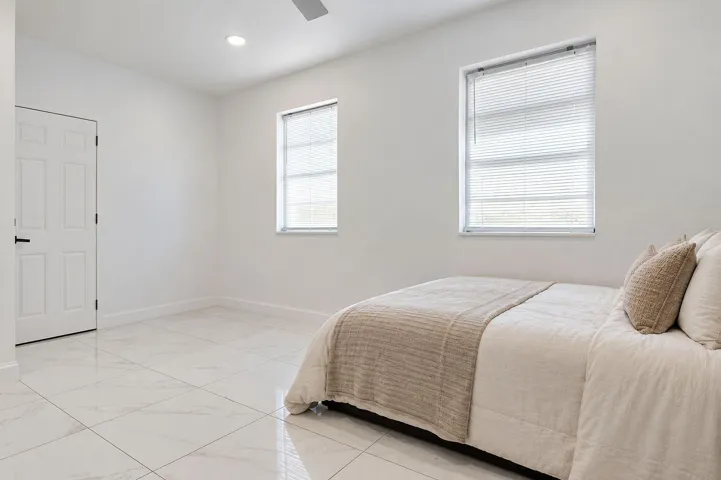 Large-format tile flooring, recessed ceiling lighting, and dual windows with horizontal blinds