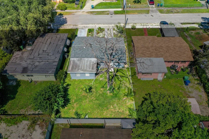 Aerial perspective of a property featuring a rectangular lot, shingle roofing, concrete driveway, and a rear perimeter fence