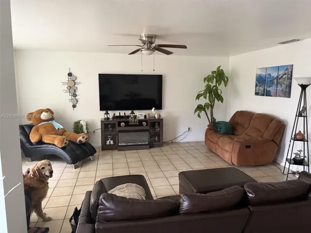 Living area featuring tile flooring, ceiling fan, and built-in electric fireplace console