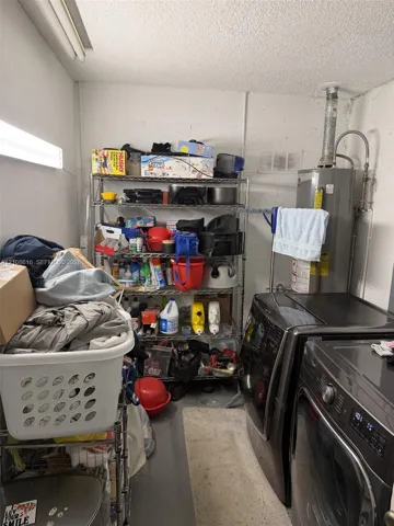 Utility space featuring a vertical tank water heater and wall-mounted fluorescent lighting