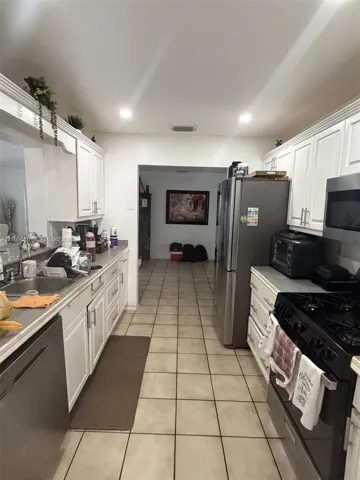 Kitchen featuring white shaker-style cabinetry, stainless steel appliances, recessed ceiling lighting, and tile flooring