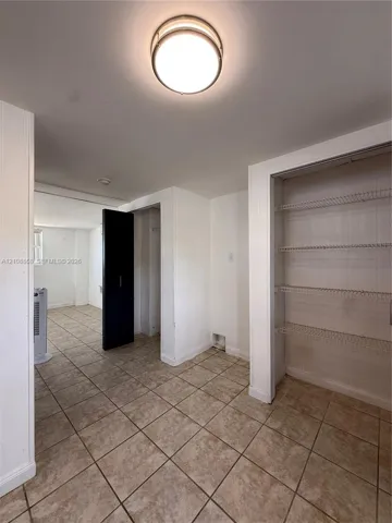 Neutral-toned ceramic tile flooring, built-in wire shelving, and a flush-mount circular ceiling fixture