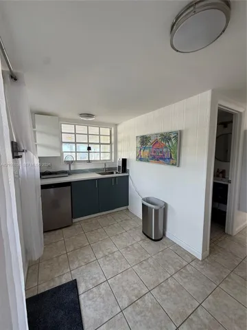 Kitchenette featuring flat-panel cabinetry, a light-toned countertop, integrated sink, and tile flooring