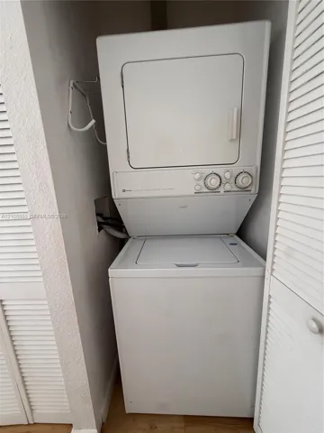 Stacked white washer and dryer unit enclosed by bi-fold louvered doors