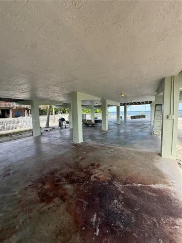 Elevated foundation featuring reinforced concrete structural supports, expansive covered hardscaping, and water frontage