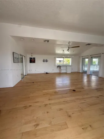 Open-concept living space featuring wood-finish flooring, vaulted ceilings, recessed lighting, a ceiling fan, and sliding glass doors