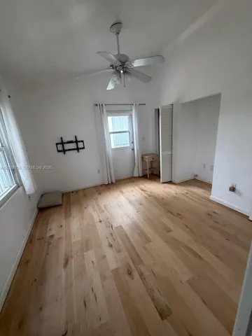 Vaulted ceilings, wood-finish flooring, ceiling fan with integrated lighting, and louvered closet doors