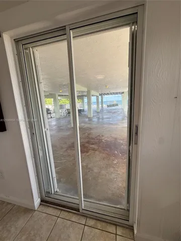 Sliding glass door opening to a covered ground-level patio with structural support columns and tile flooring
