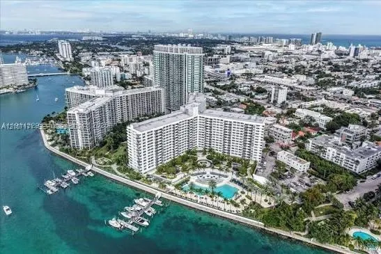 Aerial perspective of a waterfront residential complex featuring a swimming pool, boat slips, and coastal landscaping