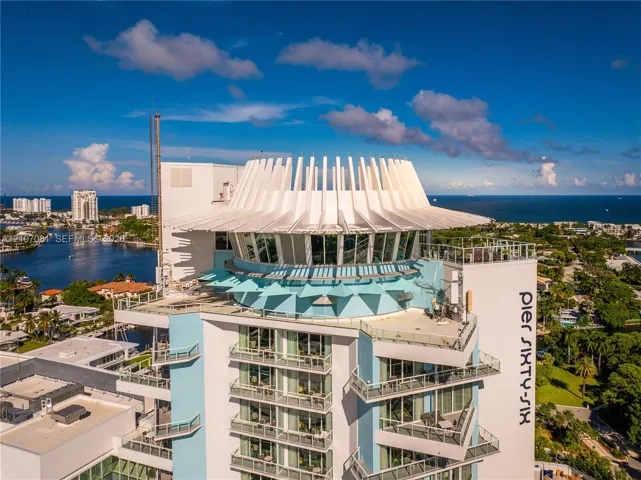 High-rise building featuring a distinctively sculpted crown, expansive floor-to-ceiling glass windows, tiered private balconies, and a reinforced concrete exterior