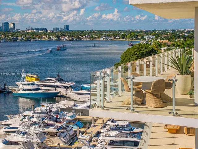 Expansive private terrace featuring light-toned tile flooring and a glass panel railing overlooking a deep-water marina and coastal waterway