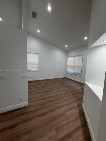 Vaulted ceiling with recessed lighting, wood-finish flooring, and built-in display niche