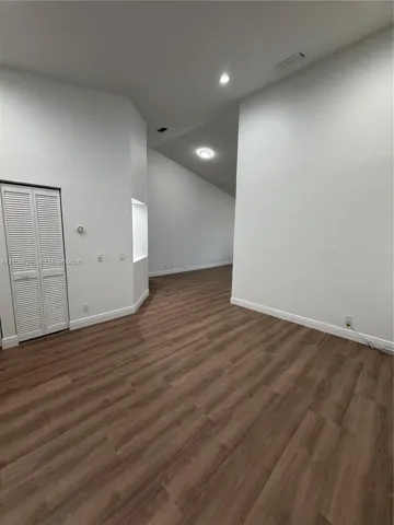 Interior space featuring vaulted ceilings, wood-finish flooring, recessed lighting, and a built-in wall niche with closet storage