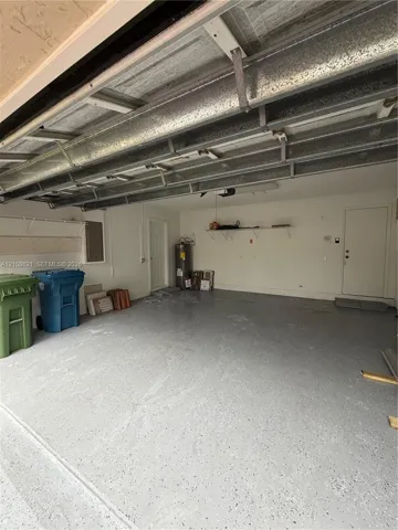 Multi-car garage featuring a speckled epoxy floor coating, painted interior walls, built-in shelving, and two access doors