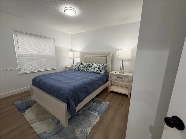 Neutral wall tones, wood-finish flooring, and flush-mount ceiling lighting, complemented by a window with horizontal blinds
