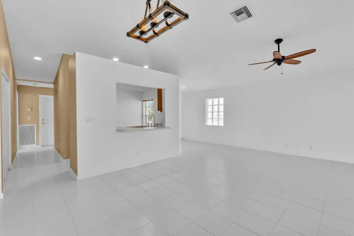 Vaulted ceilings, tile flooring, multi-blade ceiling fan, and linear pendant lighting fixture